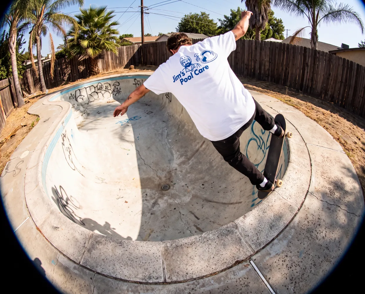 Skater carving an empty backyard pool in the white Service Tee